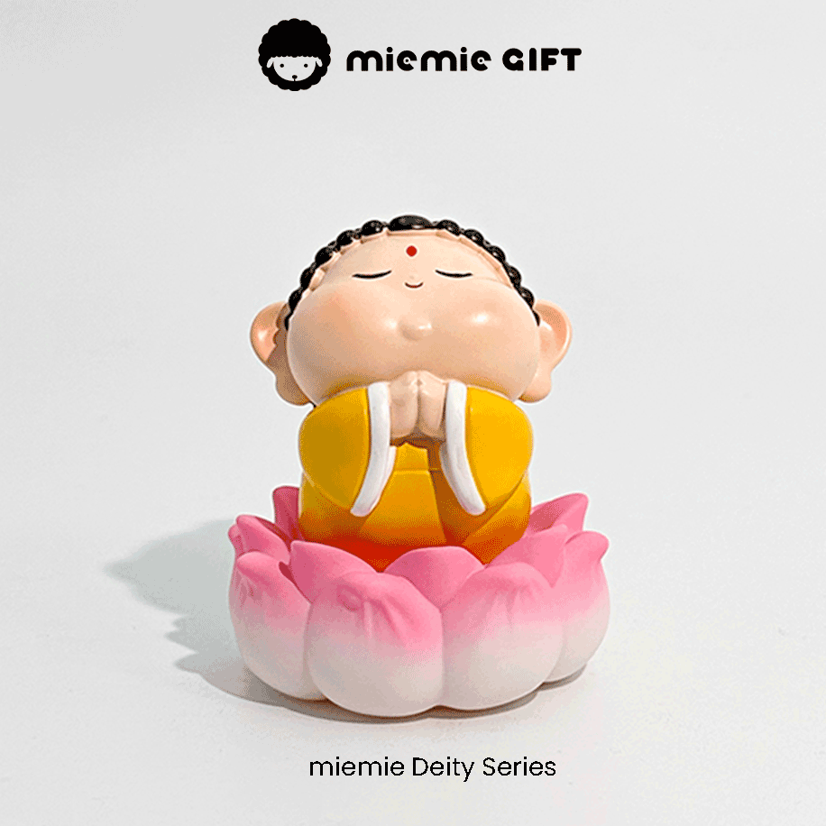 Meditative Buddha statue with colorful robes and a pink lotus flower base