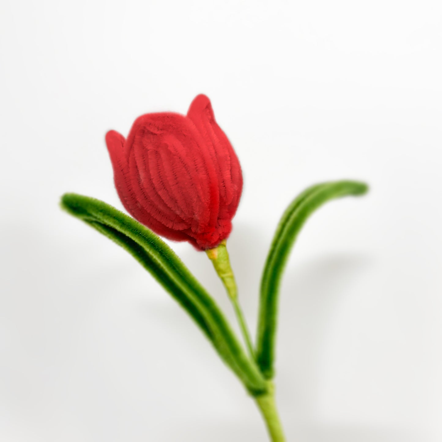  Vibrant red pipe cleaner tulip with lush green leaves, ideal for home decor, floral crafts, and handmade bouquets.