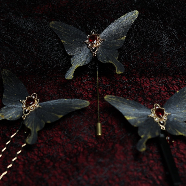 Set of gray butterfly velvet flower hairpins, each featuring a red crystal centerpiece and delicate gold details, elegantly displayed against a dark lace and deep red background.